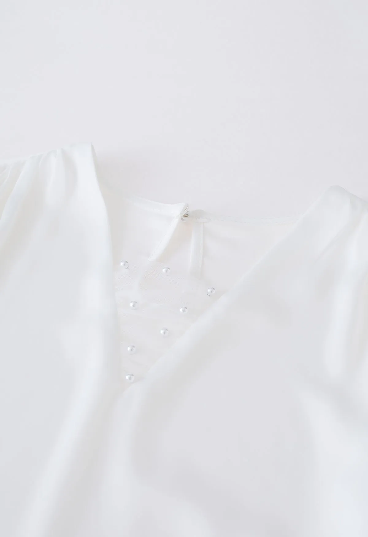 Haut en satin à col en V et maille perlée en blanc
